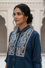 Woman wearing a blue embroidered shirt with a neutral background