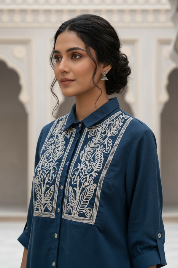Woman wearing a blue embroidered shirt with a neutral background