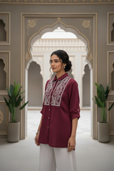 Woman wearing a maroon embroidered shirt in an ornate architectural setting