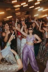 Group of people dancing in a festive setting with mirror reflections.