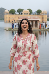 Woman in a floral outfit standing by a lake with a palace in the background