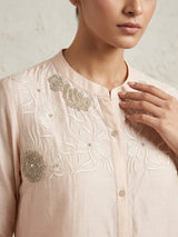 Beige embroidered shirt worn by a person on a neutral background